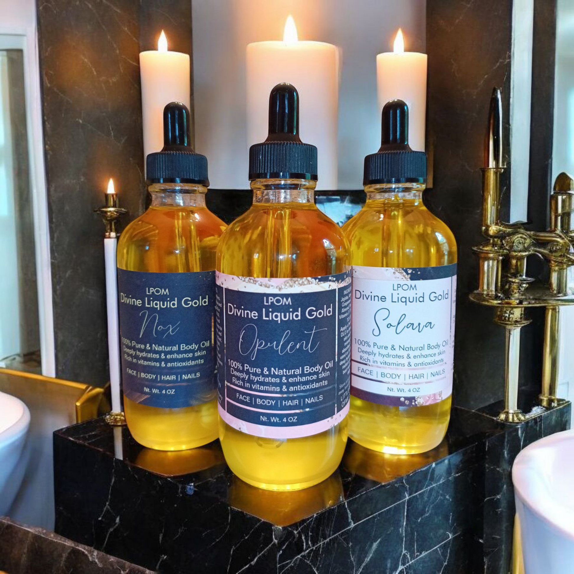 3 4Oz glass bottle droppers with labels that read Divine liquid gold in their sense sitting on a black sleek marble ledge in the bathroom behind the bottles are three candlesticks there's some gold accents along the walls