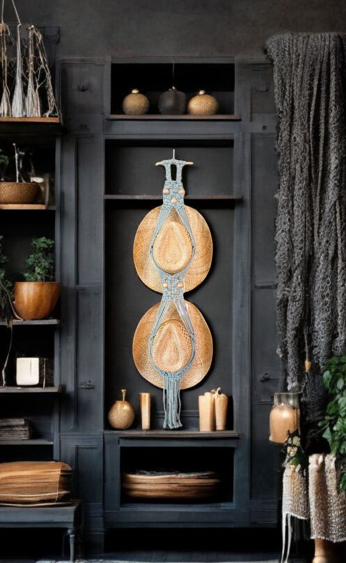 Really dark wooden backdrop of walls that have wooden shelves a curtain lays down one side there's candles and decorations all surrounding the centerpiece of a teal macrame wall hanging that holds hats holds two one underneath the other in a lovely background setting macrame hat hanger is hanging on the wall being the centerpiece