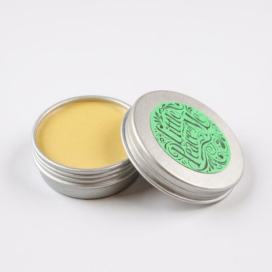 Lip balm size 10 with liquid bone inside the lid is leaning on part of the side with a little green label that reads Little piece of Me 10 is sitting on a white background with a light shadow