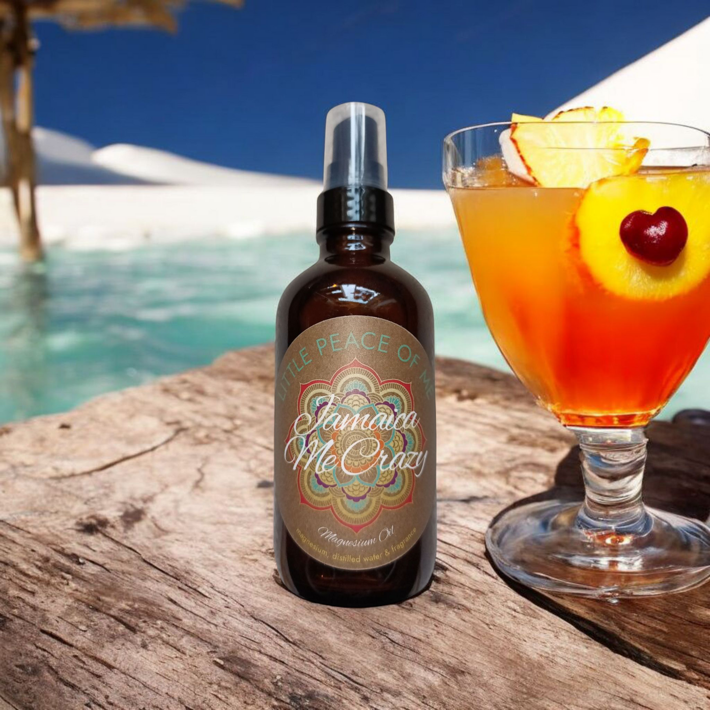 4 oz Boston dark spray bottle with a tan label that reads little piece of me Jamaican Me Crazy displayed on a Driftwood table displayed next to an hourglass shaped glass with a tropical drink inside that's orange with some pineapple and cherry on the lid sitting on the scene of a beach with the water in the background and a gazebo to the side