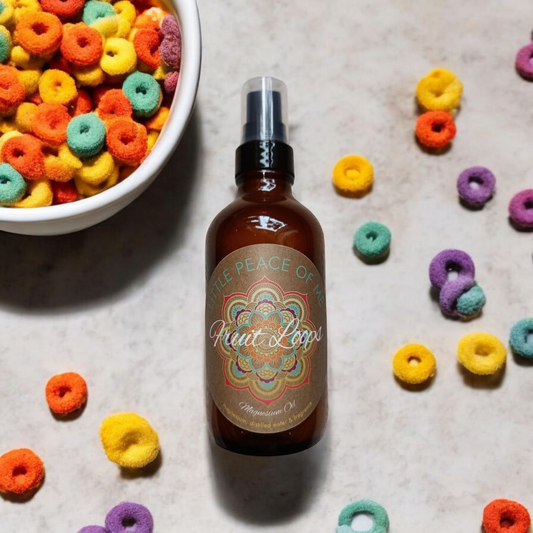 4 oz Boston spray bottle that reads Little piece of Me fruity loops magnesium oil laid on a sleetstone backdrop with fruit loop rings laying around it sitting along the side of a bowl full of fruit loop cereal bowl and bottle have a light shadow